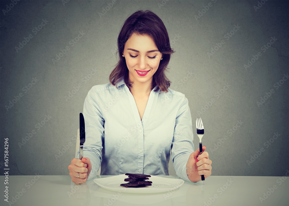Woman sitting at table smiling looking at her desert chocolate cake Woman sitting at table smiling looking at her desert chocolate cake