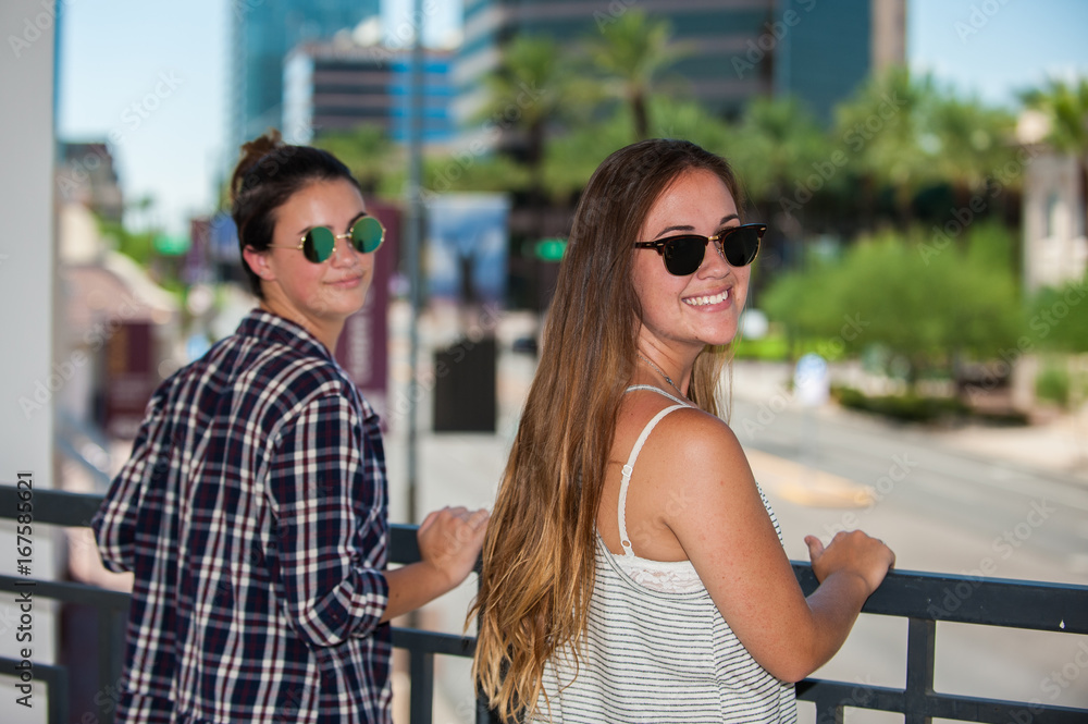 Sisters looking over Phoenix downtown streets while leaning on handrail.