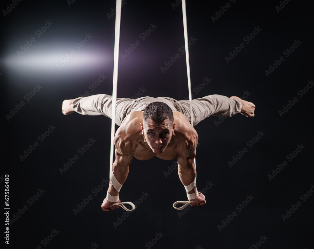 circus artist on the aerial straps with Strong muscles on black