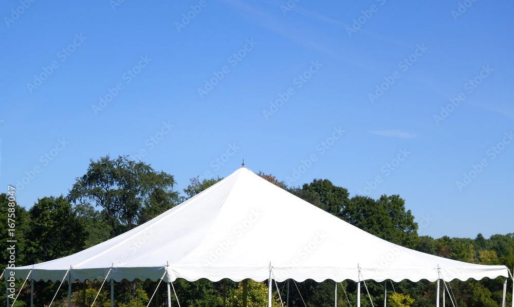 white events tent top against a tree background and a blue sky