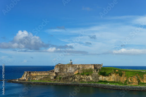 Scenic view of historic colorful Puerto Rico city in distance with fort in foreground from the sea (cruise ship)