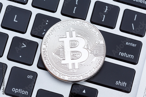 Silver bitcoin isolated on computer key board background. photo