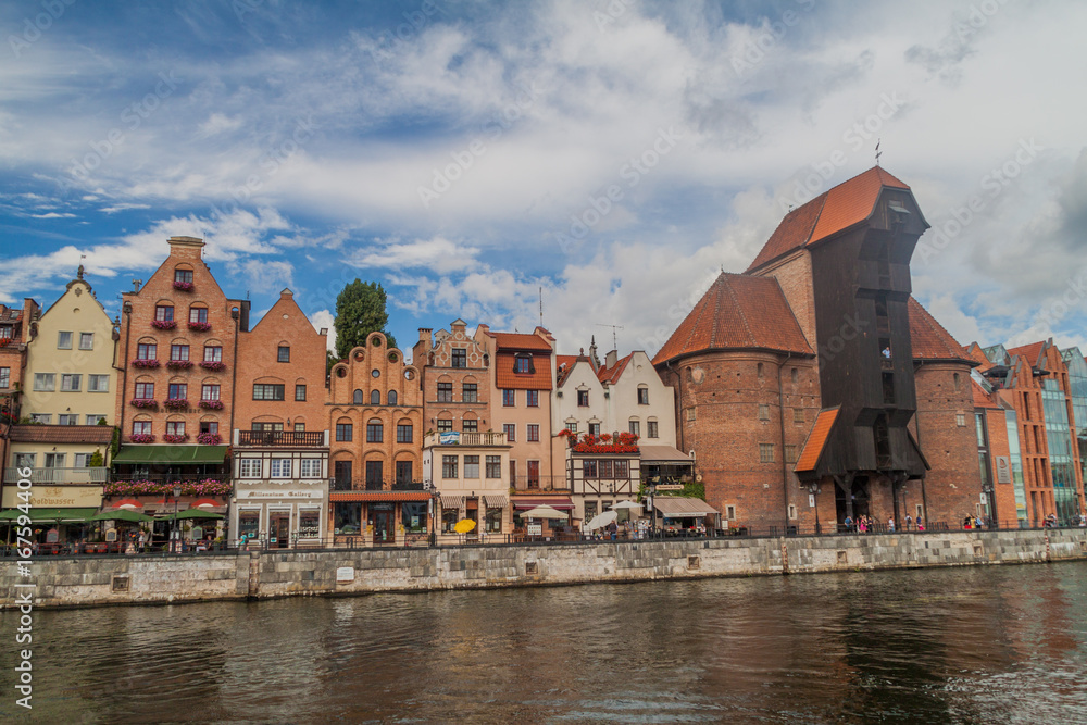 Naklejka premium GDANSK, POLAND - SEPTEMBER 2, 2016: Riverside houses by Motlawa river in Gdansk, Poland. Medieval crane in the background.
