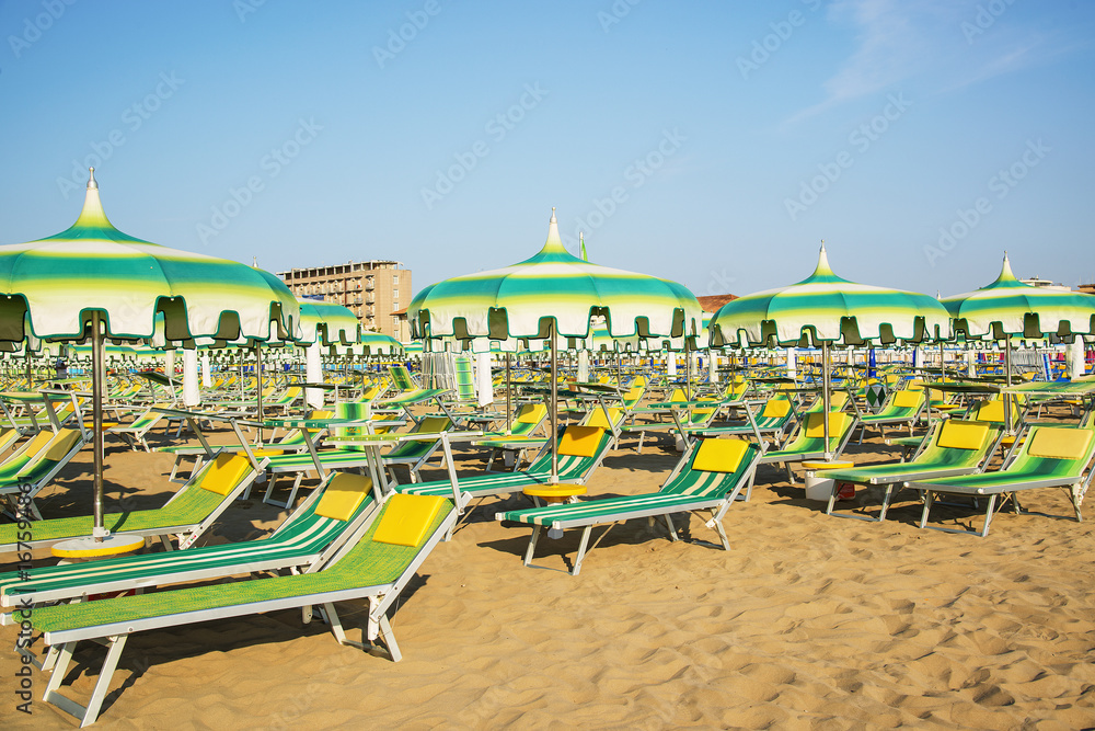 Green umbrellas and chaise lounges on the beach of Rimini in Italy