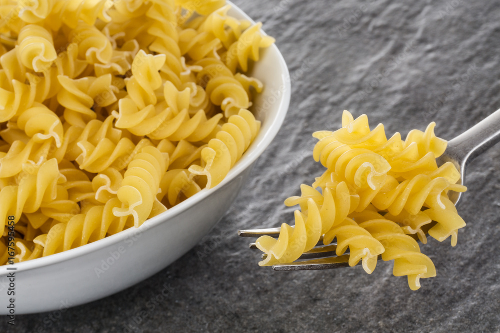 Nudeln, Pasta, Penne, Fusilli, roh, auf dunklem Granit Nudeln, Pasta, Penne, Fusilli, roh, auf dunklem Granit