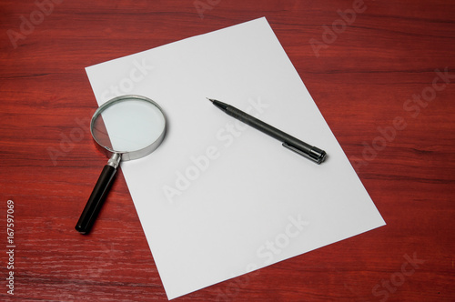 Blank sheet of paper with a pencil and a magnifying glass