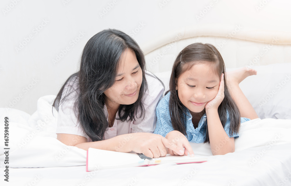 Mother and daughter reading book on bed Mother and daughter reading book on bed