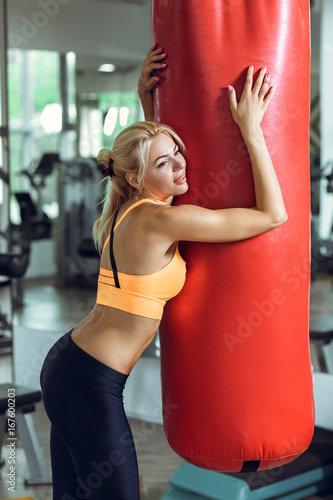 Tired young woman training with punching bag after training at gym