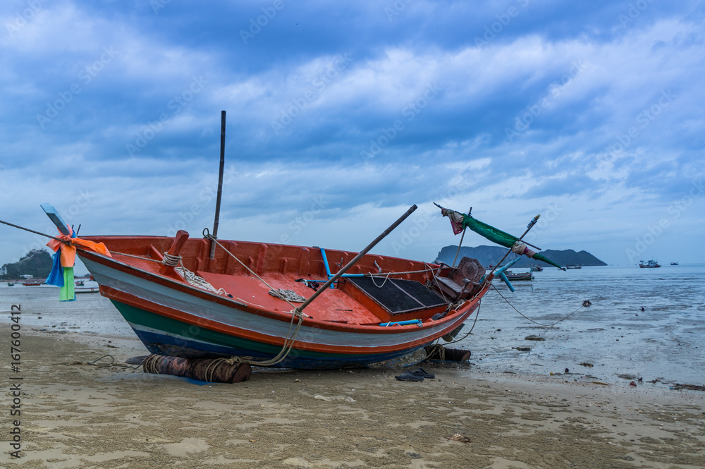 Fototapeta premium alone Fishing boat on the beach cloudy background