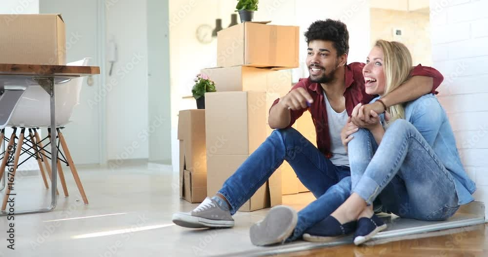 Young couple unpacking cardboard boxes at new home moving in concept Young couple unpacking cardboard boxes at new home moving in concept
