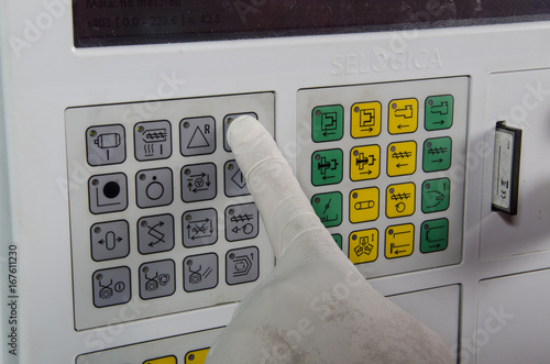 Worker hands operate keyboard of a CNC machine in the workshop of the metal factory