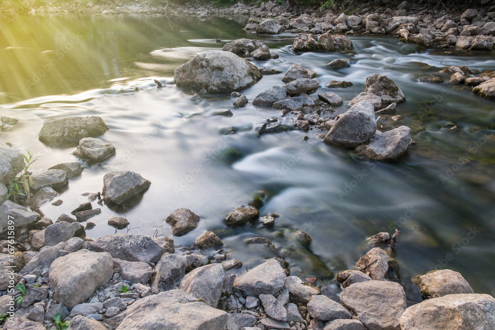 Mountain river flowing over the rocks with sun beams. Blurred water effect with long exposure Mountain river flowing over the rocks with sun beams. Blurred water effect with long exposure