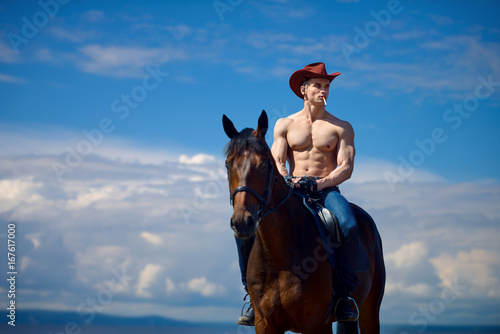 Macho man handsome cowboy and horse on the background of sky and water.