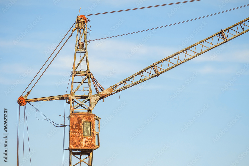 Cabin of old abandoned rusty tower crane on a blue sky background