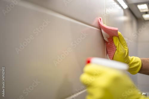 Man cleaning kitchen furniture by yellow cloth