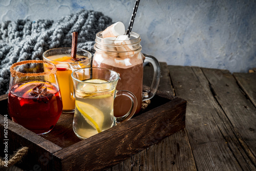 Selection of various autumn traditional drinks: hot chocolate with marshmallow, tea with lemon and ginger, white pumpkin spicy sangria, mulled wine. On wooden rustic table, copy space, selective focus photo