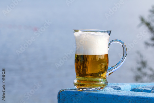 Mug of beer on the table by the lake