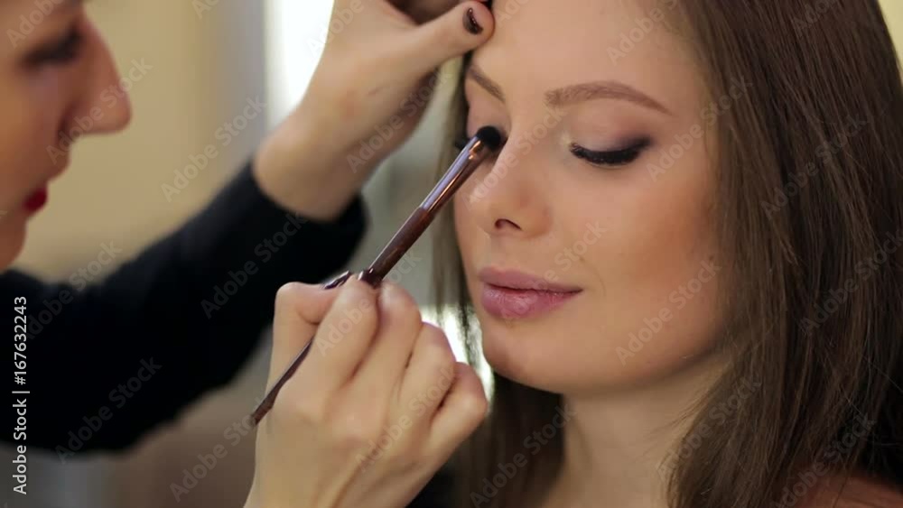 Professional Make-up artist doing glamour model make-up at work. Portrait of beautiful young woman. Make-up artist applies eye shadow. Professional Make-up artist doing glamour model make-up at work. Portrait of beautiful young woman. Make-up artist applies eye shadow.