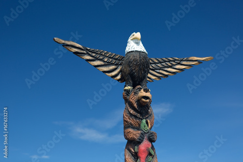 A carved wooden alaskan totem pole against blue sky