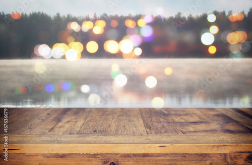 vintage wooden board table in front of abstract photo of misty and foggy lake at morning evening.
