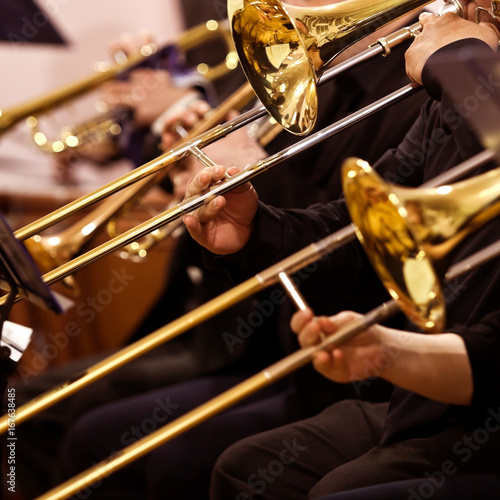 Trombones in the hands of musicians in the orchestra closeup