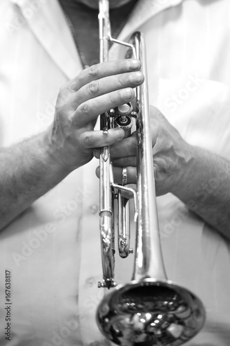 Hands of a musician playing on a trumpet closeup in black and white tones