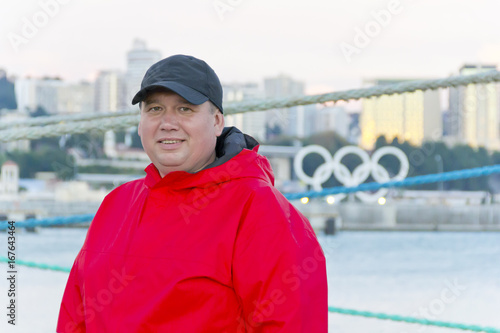 Big fat man in red jacket on embankment