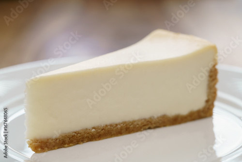slice of traditional new york cheesecake on white plate on wood table