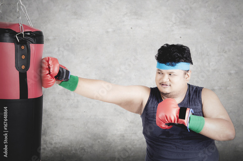 Obese person punches boxing sack © Creativa Images