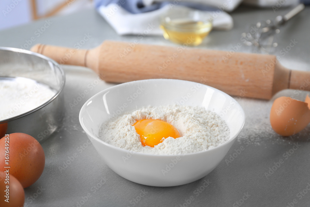 Bowl with flour and egg on kitchen table Bowl with flour and egg on kitchen table