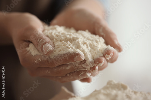Female chef holding white flour in hands at kitchen