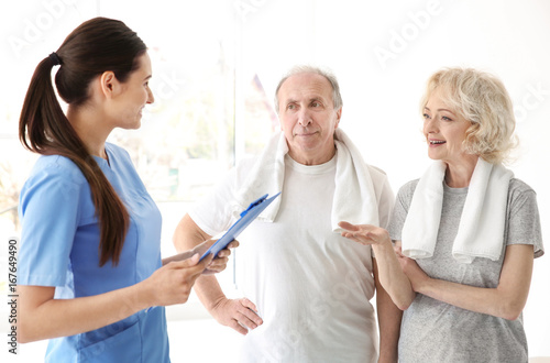 Physiotherapist with elderly patients in modern clinic