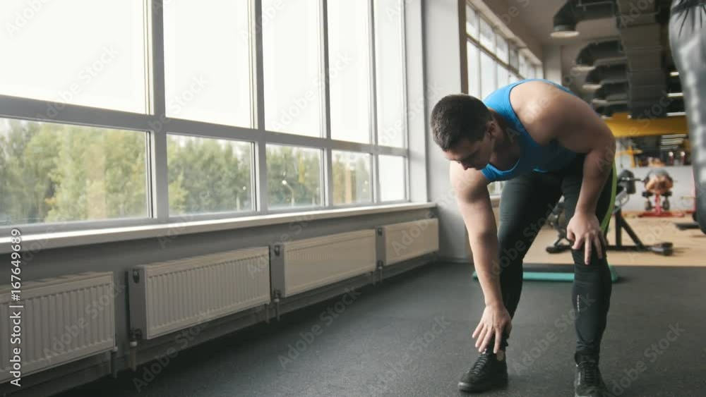 Man bodybuilder doing exercises for warm-up in the gym Man bodybuilder doing exercises for warm-up in the gym