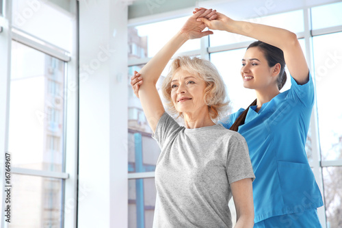 Physiotherapist working with elderly patient in clinic photo