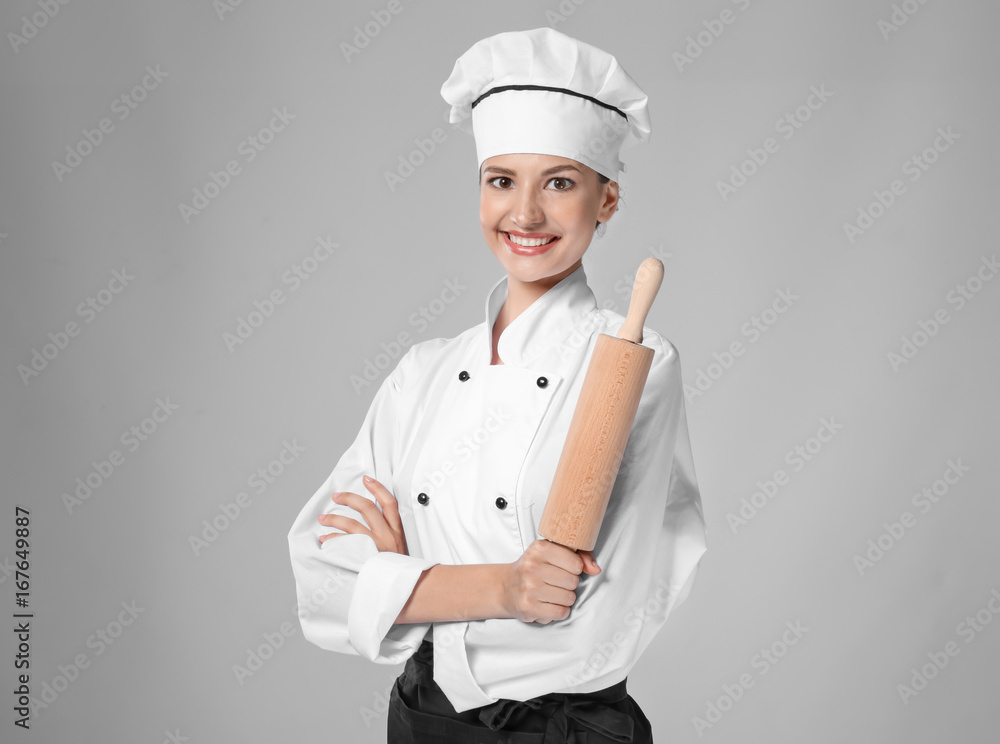 Young female chef with rolling pin on light background Young female chef with rolling pin on light background