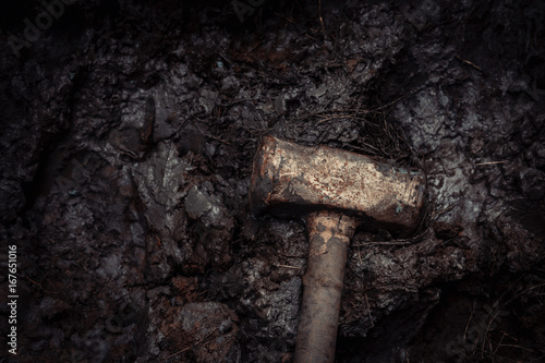 old rusty iron construction hammer on the mud, warm tone photography and film style.