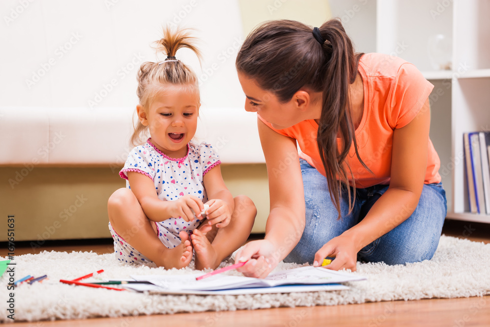 Fototapeta premium Mother and daughter in their home. They are looking at coloring book.