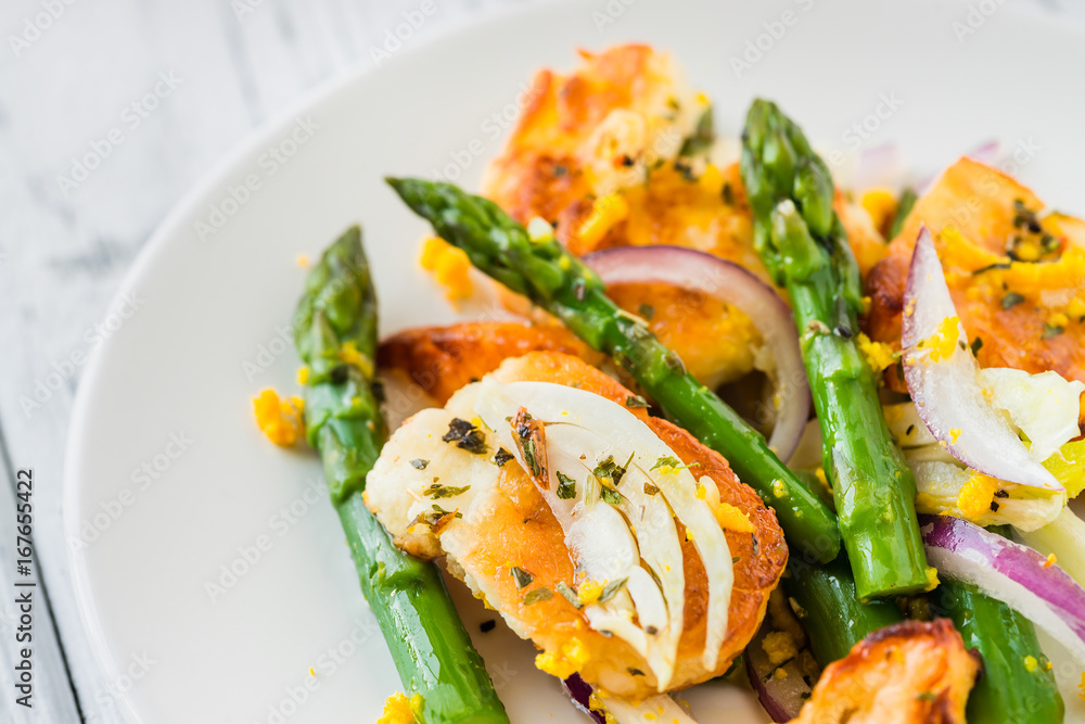 Salad with fried halloumi, asparagus and orange zest. Close up. White wooden background Salad with fried halloumi, asparagus and orange zest. Close up. White wooden background