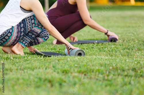 Photos Two young women keeping fit by doing yoga in the summer green park