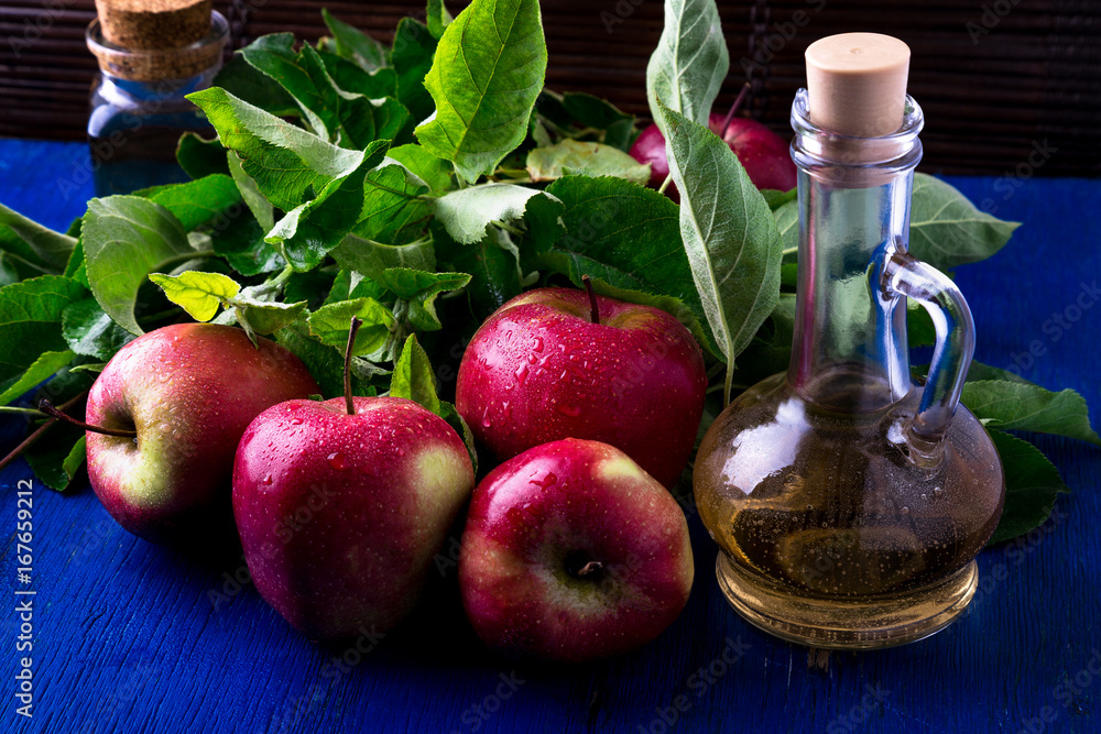 Apple cider vinegar. Three glass bottle on blue background. Red apples Apple cider vinegar. Three glass bottle on blue background. Red apples