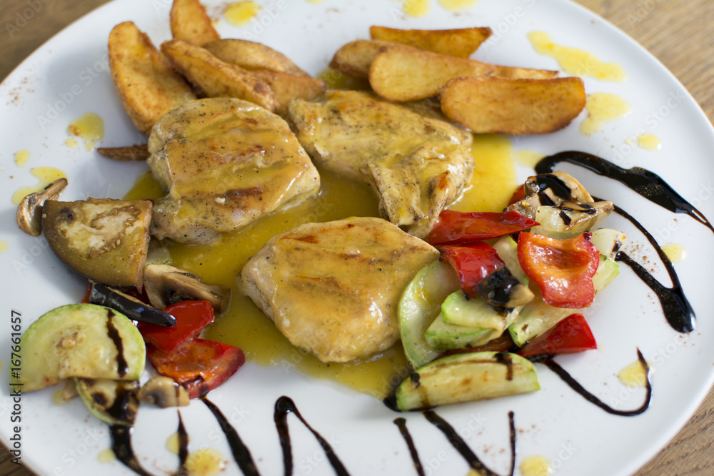 Grilled chicken breast with vegetables and sauce on a plate. Traditional cuisine. Grill kitchen. Grilled chicken breast with vegetables and sauce on a plate. Traditional cuisine. Grill kitchen.
