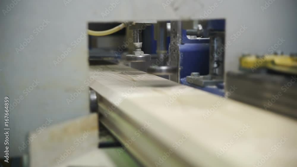The board moves in a special device. Production line in woodworking factory The board moves in a special device. Production line in woodworking factory