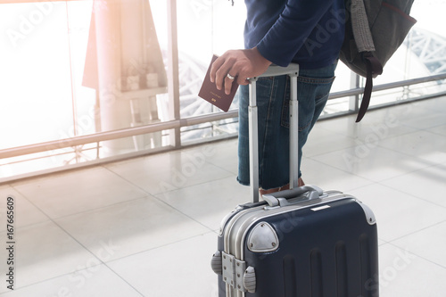 Close up of man hand holding passport and luggage suitcase at airport