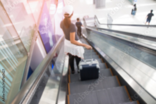 BANGKOK, THAILAND - AUGUST 8, 2017: Blurred background of asian woman with luggage suitcase on escalators at Suvarnabhumi Airport. The most popular SE Asia aviation hub.