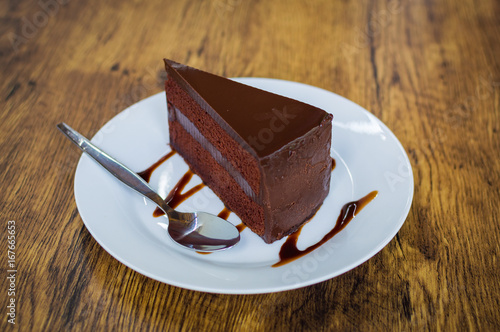 Piece of chocolate cake with spoon on white plate photo