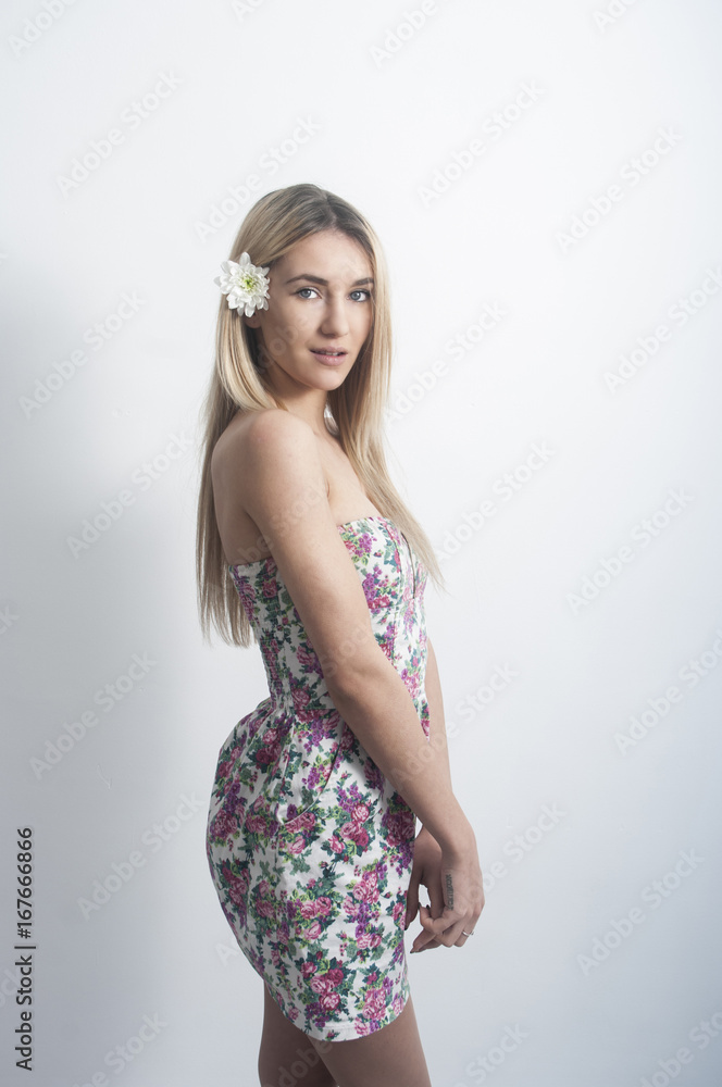 Portrait of a beautiful and gentle blonde girl in the studio on a blue background in the dress, the concept of beauty and health