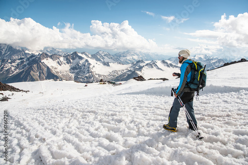 The tired traveler descends from the snowy top against the background of snow-capped mountains