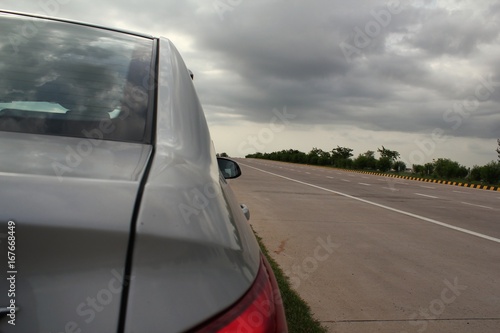Side view of car parked on a highway roadside with cloudy skies