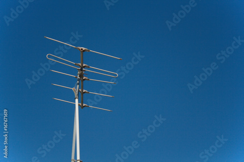 An old TV antenna against a clear blue sky. © Karen