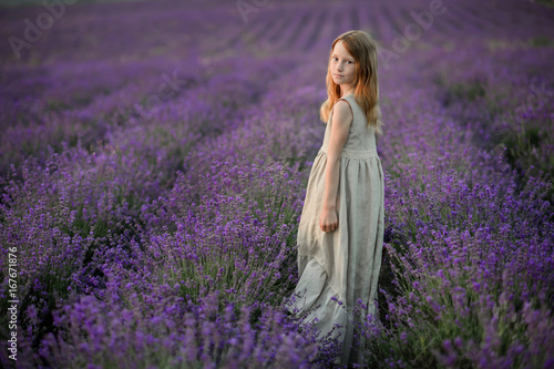 Beautiful girl in a field of lavender on sunset. Beautiful girl in amazing dress walk on the field of lavender.